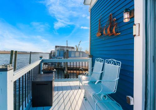 a balcony with two chairs and a blue house at Jones Beach Houseboat in Seaford