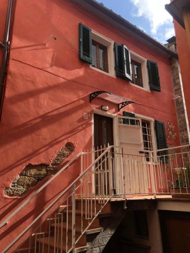 a red building with a balcony and windows at Il Vicolo in Buti