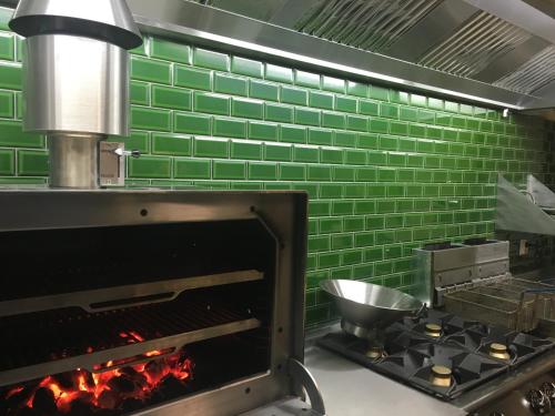 a kitchen with a stove and a green brick wall at Beach Hotel Katwijk in Katwijk