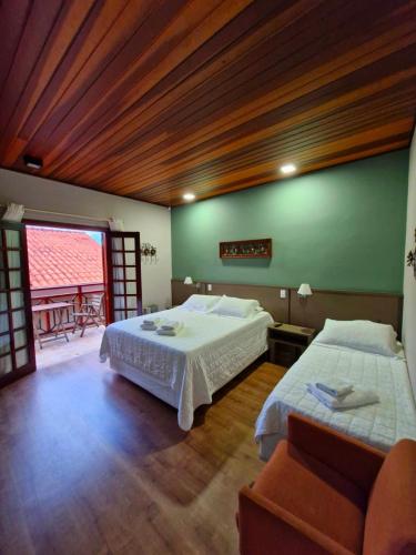 a bedroom with two beds and a green wall at Pousada Cantinho da Serra in Campos do Jordão