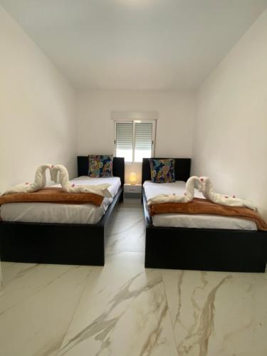 two beds in a room with white walls and marble floors at REQUESENS Playa in Empuriabrava