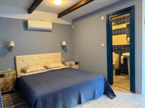a bedroom with a bed with a blue bedspread at Charming Cozy Home on the Beach in Kaluđerac
