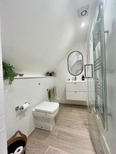 a white bathroom with a toilet and a mirror at Charming 2B Georgian Flat in Historic Tring in Tring