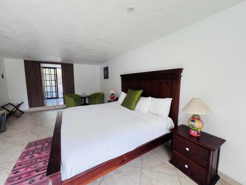 a bedroom with a large white bed and a table at Hotel Las Puertas de Tepoztlan in Tepoztlán