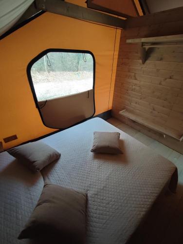 a bed in a small room with a window at Il Lago dei Cigni - Glamping & Restaurant in Corsalone