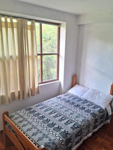 a bed in a bedroom with a window at Hostal Aylluq Wasin Casa de Familia-Guest House, habitación Familiar in Urubamba
