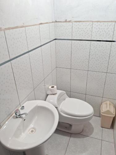 a bathroom with a toilet and a sink at Hostal Aylluq Wasin Casa de Familia-Guest House, habitación Familiar in Urubamba