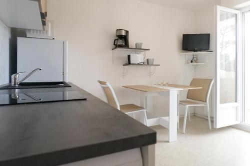 une cuisine avec une table et un réfrigérateur blanc dans l'établissement Grand Studio proche mer quartier de la Pironnière - 4 personnes, à Les Sables-dʼOlonne