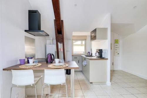 - une cuisine avec une table et des chaises blanches dans l'établissement Charmant T3 Cosy - Plein centre ville, à Montluel