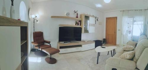 ein Wohnzimmer mit Fernseher, Couch und Sesseln in der Unterkunft Vistabella golf villa jade in Orihuela