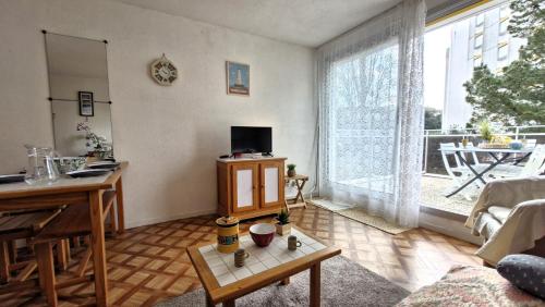 un salon avec une table et une grande fenêtre dans l'établissement Vaux sur Mer - APPARTEMENT résidence LES TROIS MOUSQUETAIRES - Plage de Nauzan, à Vaux-sur-Mer