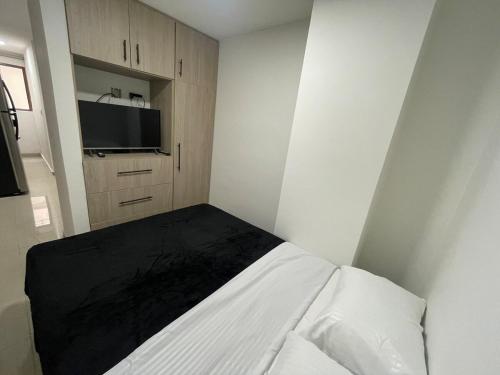 a white bedroom with a bed and a tv at Apartaloft 207 Near to hospital San Jorge in Pereira