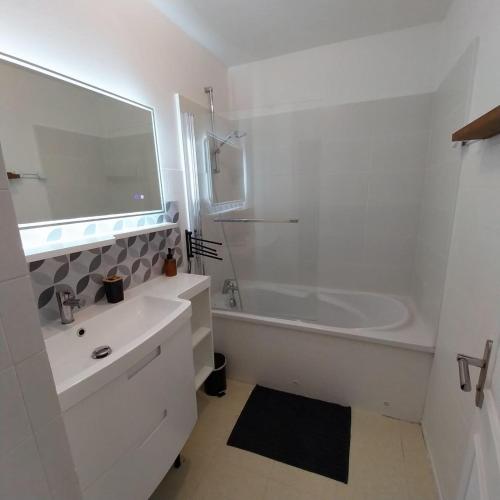 La salle de bains blanche est pourvue d'une baignoire, d'un lavabo et d'une chambre. dans l'établissement Maison de ville proche de tout, 5min du centre ville & 20min de la plage, à Quimper