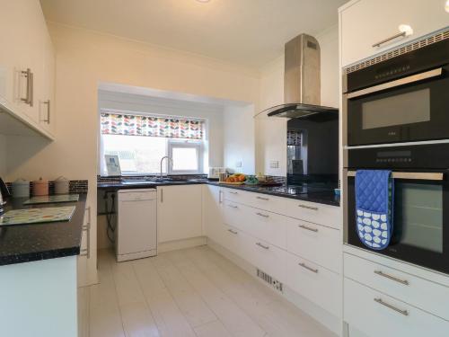 a kitchen with white cabinets and a window at Marine House in Pevensey