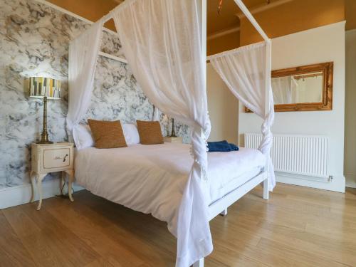 a bedroom with a white canopy bed with curtains at Marine House in Pevensey