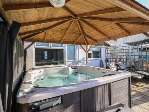 a hot tub on a deck with a wooden roof at Marine House in Pevensey