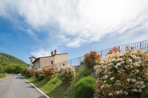 a house on the side of a road with flowers at Agriturismo I CASALI DI MORRO in Sellano