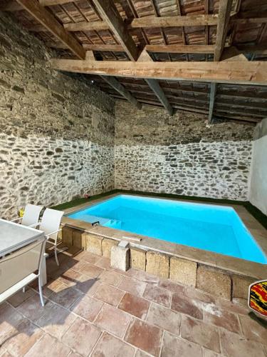 - une piscine dans un bâtiment en pierre avec une table et des chaises dans l'établissement Provencal house, swiming pool barbecue, sun and petanque, à Saint-Gervasy