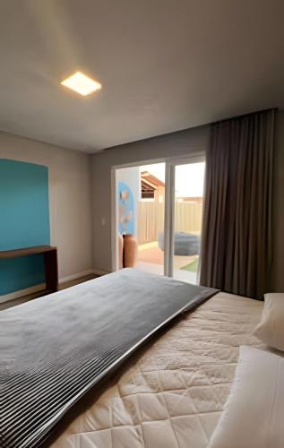 una camera da letto con un letto grande e una porta scorrevole in vetro di Anfitrya - Casa 38 a São Miguel do Gostoso