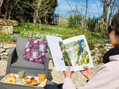 a woman reading a book while sitting on a chair at Fleurs de vigne, gîte charentais au grand coeur in Bouteville