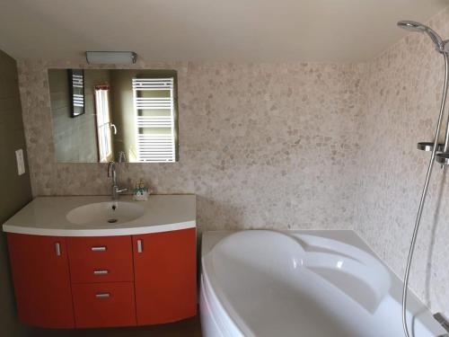 une salle de bain avec une baignoire, un lavabo et un miroir dans l'établissement Maison avec jacuzzi & jardin 6 personnes, à Noirmoutier-en-l'lle