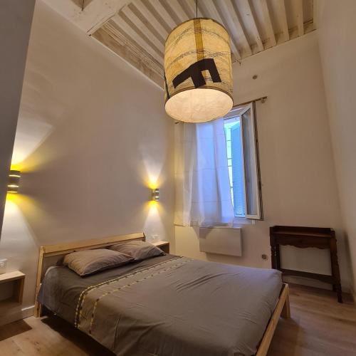 une chambre avec un lit et un lustre dans l'établissement Ambiance bois proche vieux port, T2 de caractère, à La Ciotat