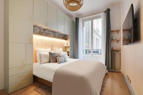 une chambre avec un grand lit blanc et une fenêtre dans l'établissement L'appartement Saint Honore, à Paris