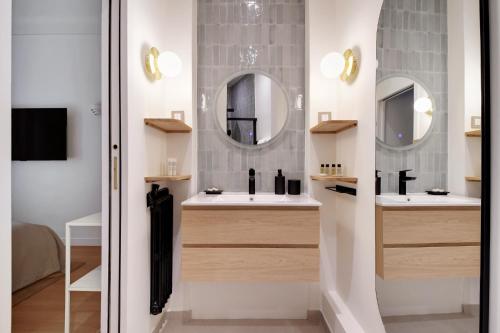 une salle de bain avec deux lavabos et deux miroirs dans l'établissement L'appartement Saint Honore, à Paris