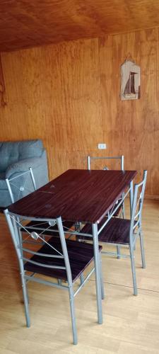 a wooden table with two chairs and a wooden wall at Cabaña Milena in Quellón