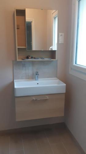 une salle de bain avec un lavabo blanc et un miroir dans l'établissement Le BOTELLA, à Teurthéville-Hague