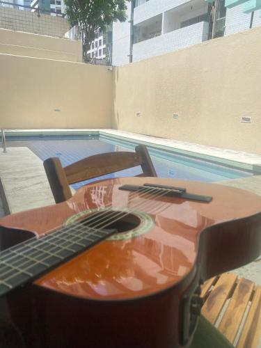 a guitar sitting on a table next to a pool at Apraiana Pousada e Hostel in Recife