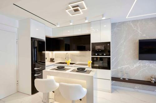 una cocina con electrodomésticos blancos y taburetes blancos en Kallimarmaro MM Smart suite by SuperHost Hub, en Atenas