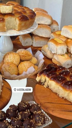une table remplie de différents types de pains et de pâtisseries dans l'établissement A Estalagem Pousada, à Monteiro Lobato