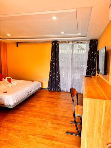 a bedroom with a bed and a tv and a wooden floor at MERAKI BEACH RESORT Lodges in Lomé