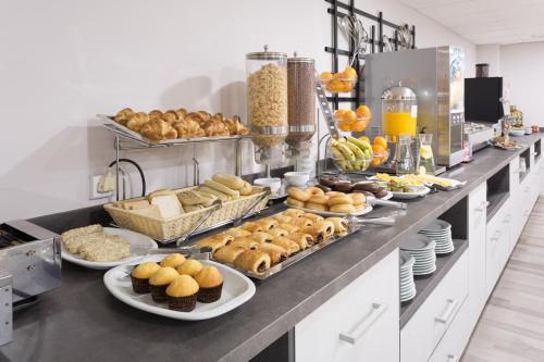 a buffet line with many different types of bread and pastries at Hotel Familia Conde in Huelva