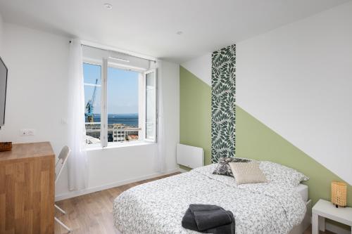 une chambre avec un lit et une grande fenêtre dans l'établissement Kenavo, à Brest