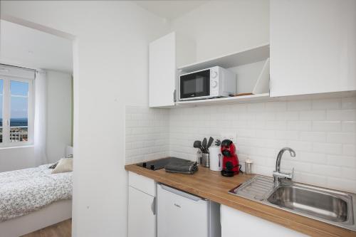 une cuisine blanche avec un évier et un micro-ondes dans l'établissement Kenavo, à Brest