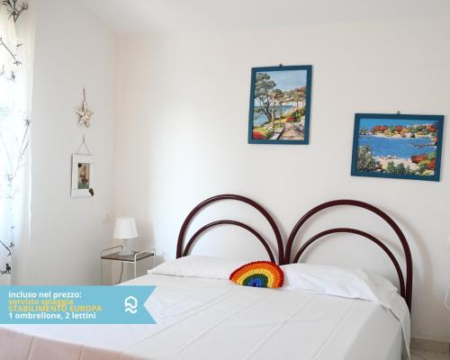 a bedroom with a bed with a rainbow pillow on it at RS322 - Marcelli, bilocale fronte mare con spiaggia inclusa in Marcelli