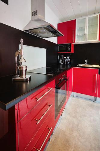 une cuisine rouge avec des comptoirs noirs et des armoires rouges dans l'établissement Cozy and Stylish with A-C in City Center!, à Strasbourg