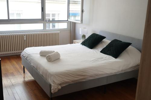 une chambre avec un grand lit blanc avec des oreillers verts dans l'établissement Le Neyst, à Lyon