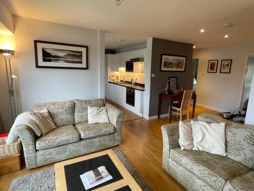 a living room with two couches and a kitchen at Ambleside 3 Bedroom Apartment in Ambleside