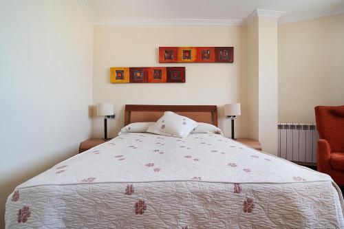 une chambre avec un grand lit et une chaise dans l'établissement Apartamentos de playa en Villajuán, à Vilagarcía de Arousa