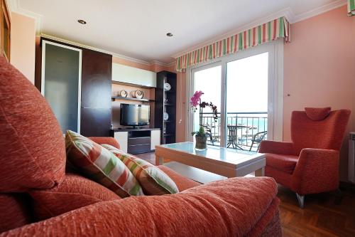 un salon avec un canapé rouge et une table dans l'établissement Apartamentos de playa en Villajuán, à Vilagarcía de Arousa