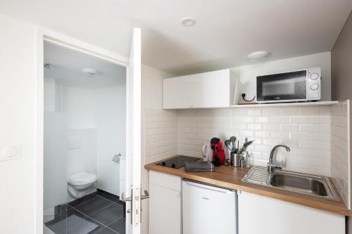 une petite cuisine avec un évier et un micro-ondes dans l'établissement Boistrudan, à Brest