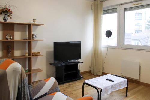 un salon avec une télévision à écran plat et un canapé dans l'établissement Lovely 1-bedroom apartment near park, à Pantin