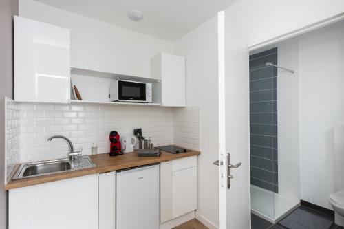 une cuisine blanche avec un évier et un micro-ondes dans l'établissement Friskette, à Brest