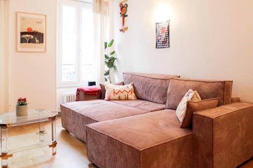 un salon avec un canapé marron et une table dans l'établissement Charming Parisian Stay Just Steps from Montmartre, à Paris