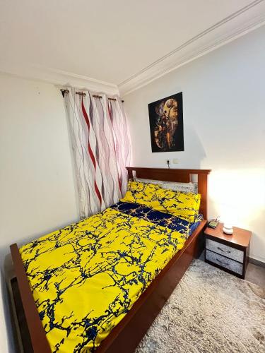 a bedroom with a bed with yellow sheets and a window at S&R Home appartement in Yaoundé