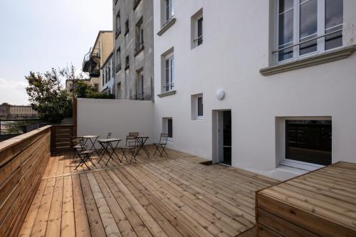 - une terrasse en bois avec des chaises et une table dans un bâtiment dans l'établissement En Distribil, à Brest