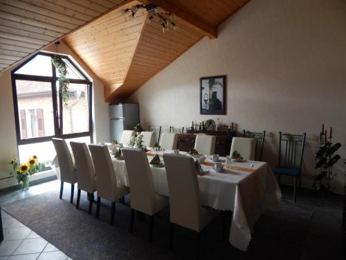 a dining room with a long table and white chairs at Gästehaus Rebstock im Weingut Schrauth-Becker in Udenheim